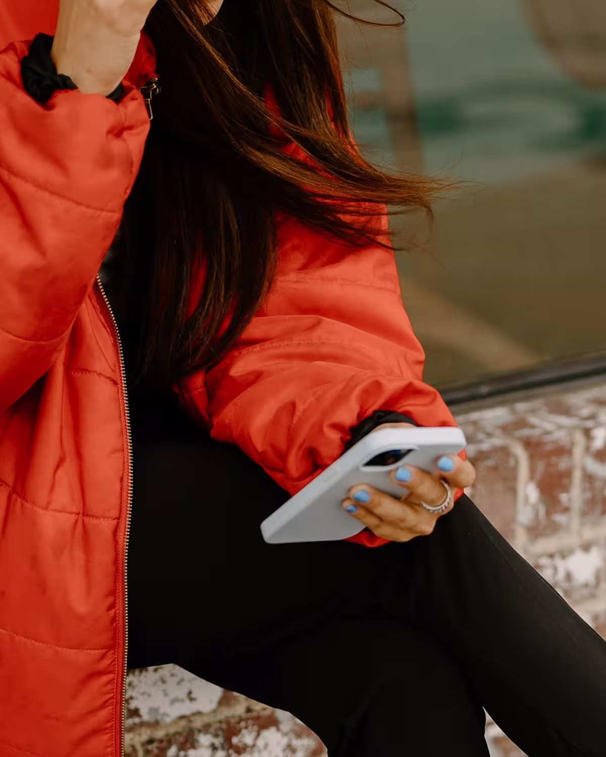 woman wearing a bright orange coat holding a mobile phone