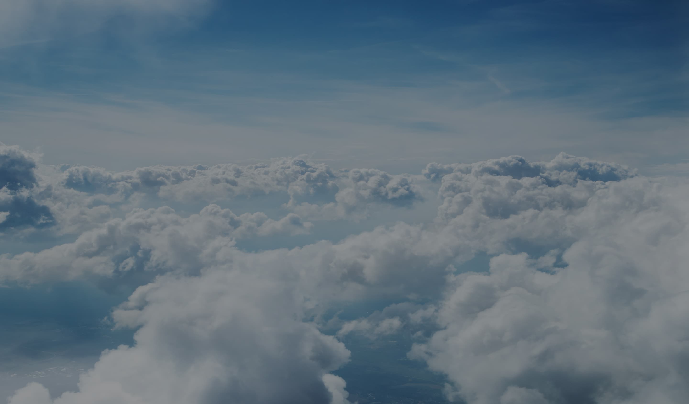 Background image showing a view above the clouds of a bright blue sky.