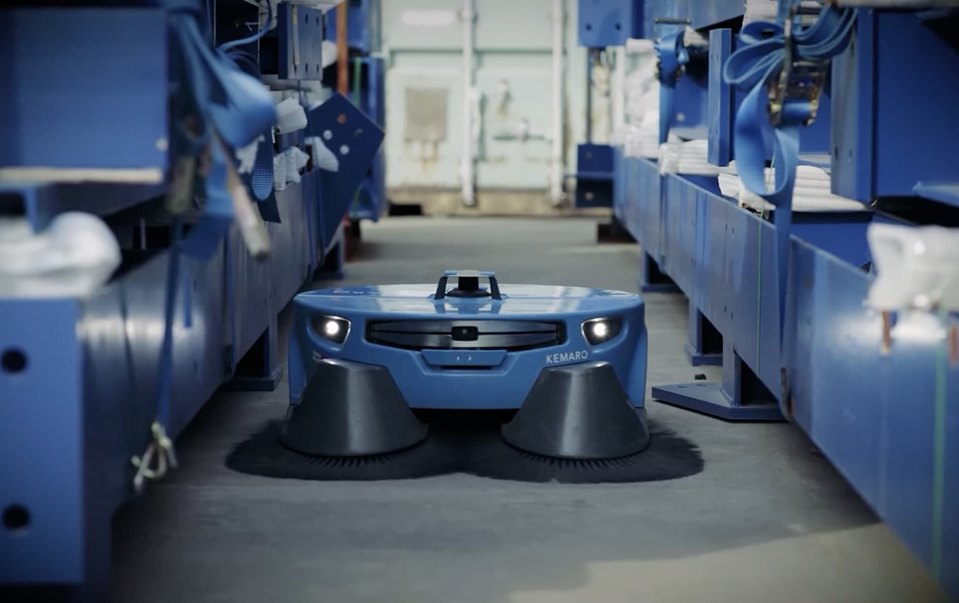 K900 inside a warehouse, sweeping on a narrow corridor between machinery