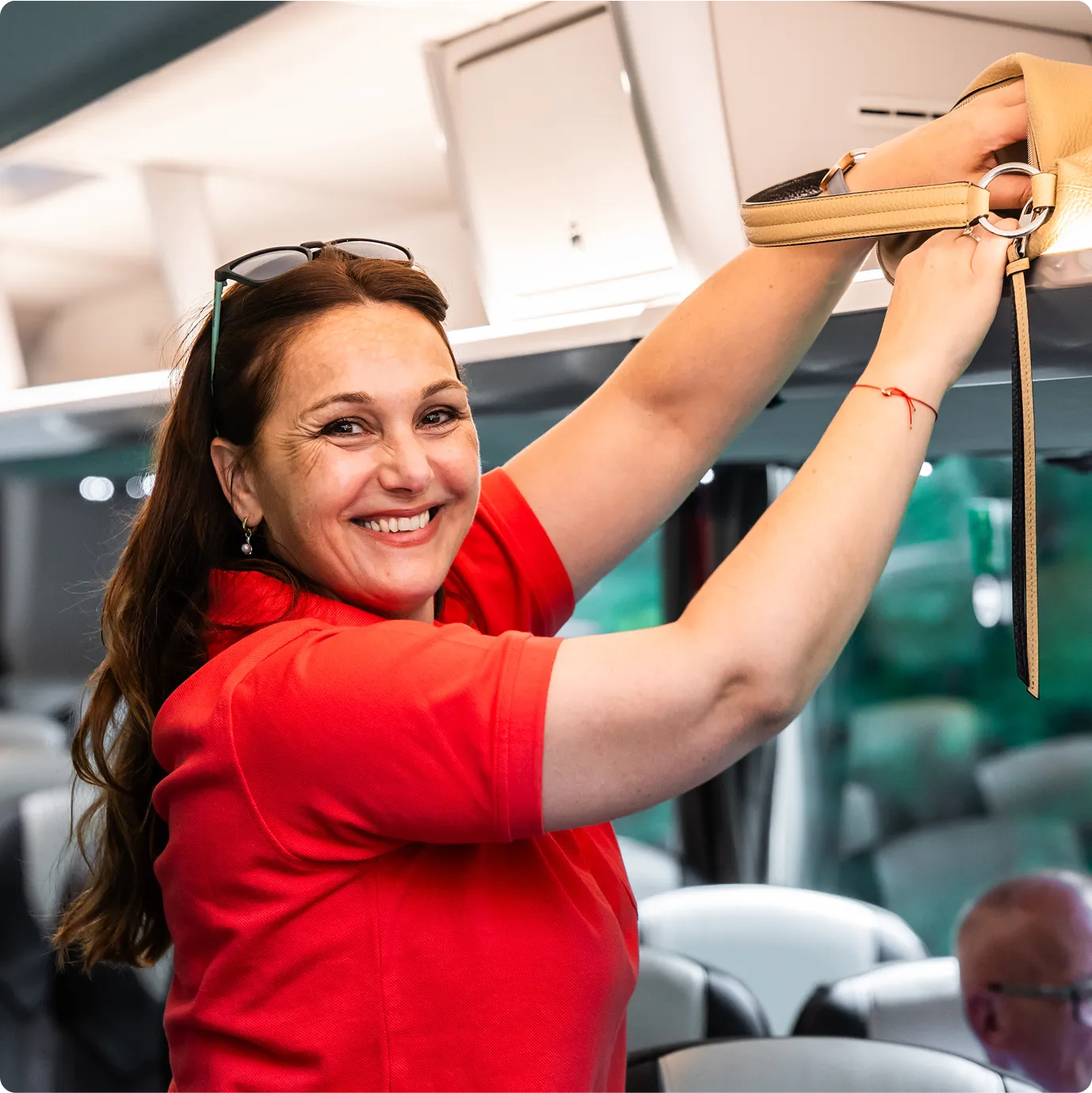 Frau legt Handtasche im Bus in Gepäckablage