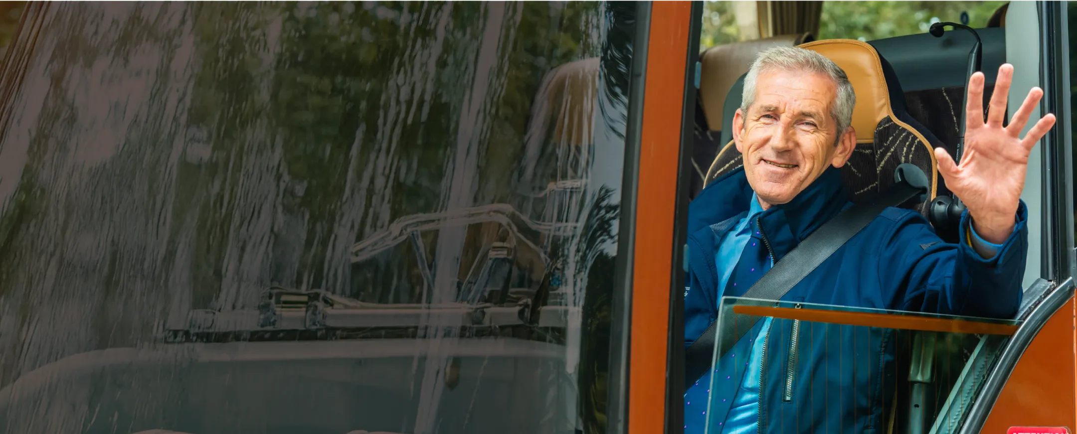Busfahrer winkt aus Fahrerkabine