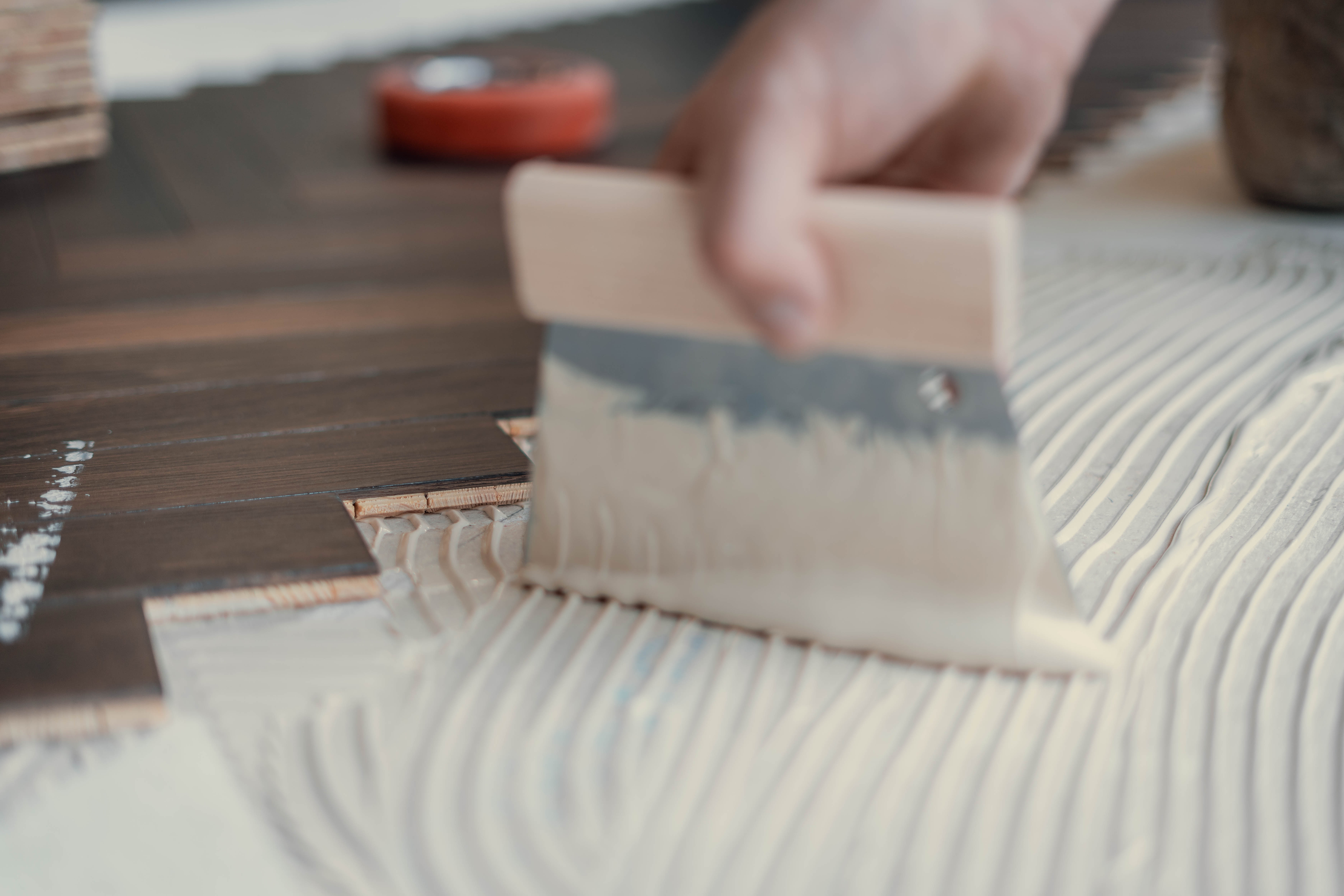 Fachgerechtes Auftragen von Parkettkleber mit einem Spachtel durch Hauptstadt Parkettleger