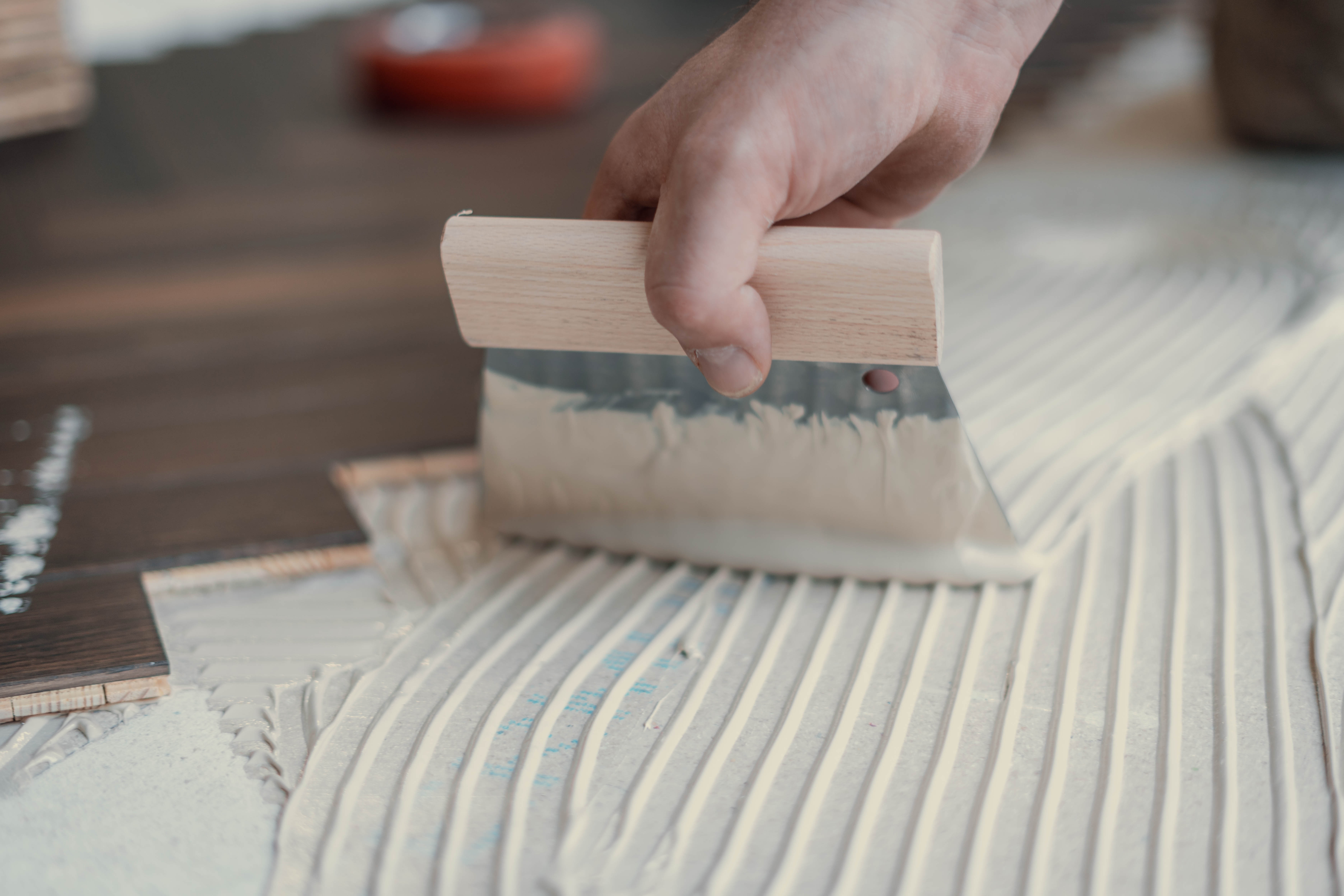 Fachgerechtes Auftragen von Parkettkleber mit einem Spachtel durch Hauptstadt Parkettleger