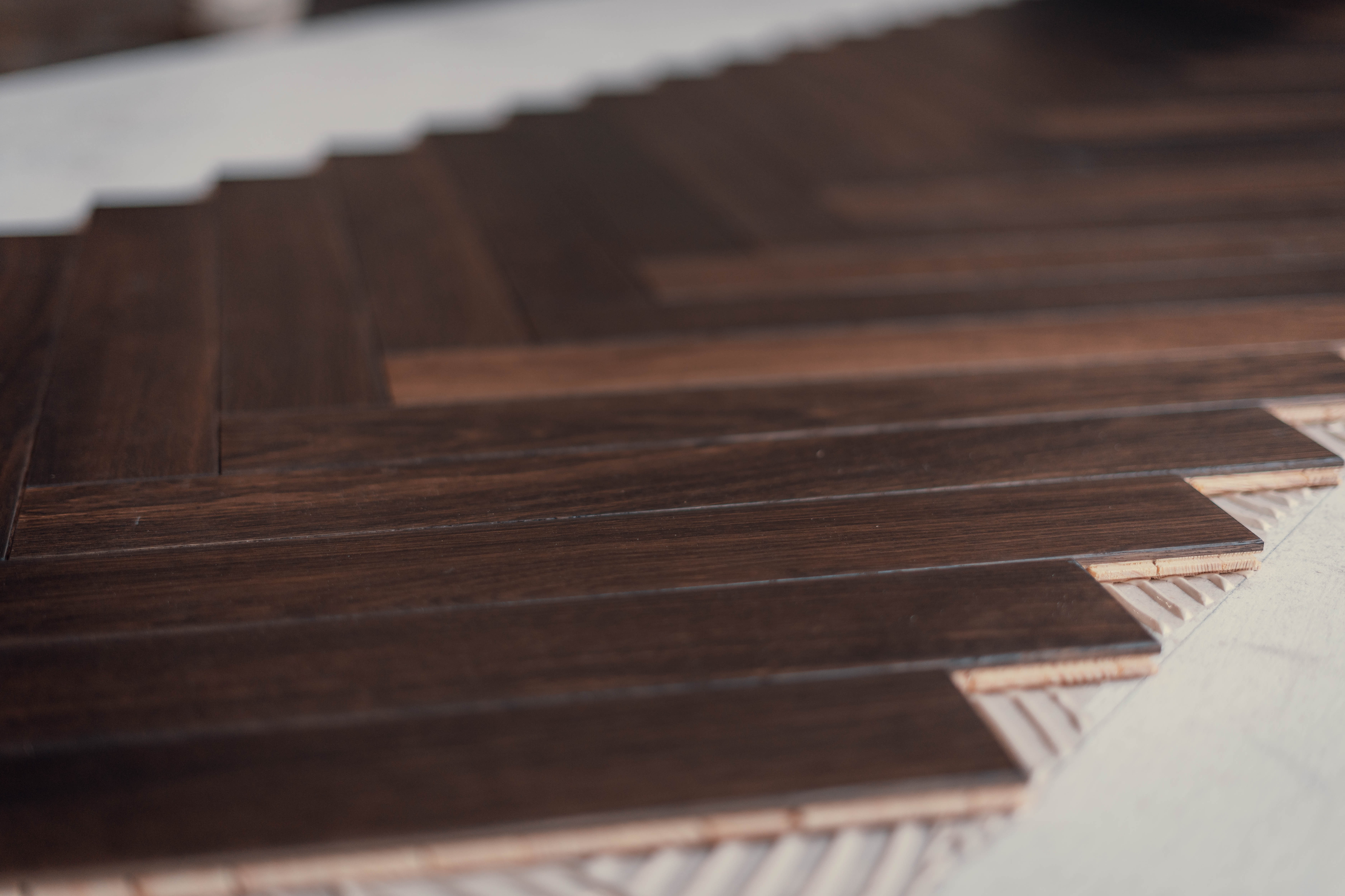 Nahaufnahme der fachmännischen Verlegung von Fischgrät-Parkett durch das Experten-Team von Hauptstadt Parkettleger in Berlin.