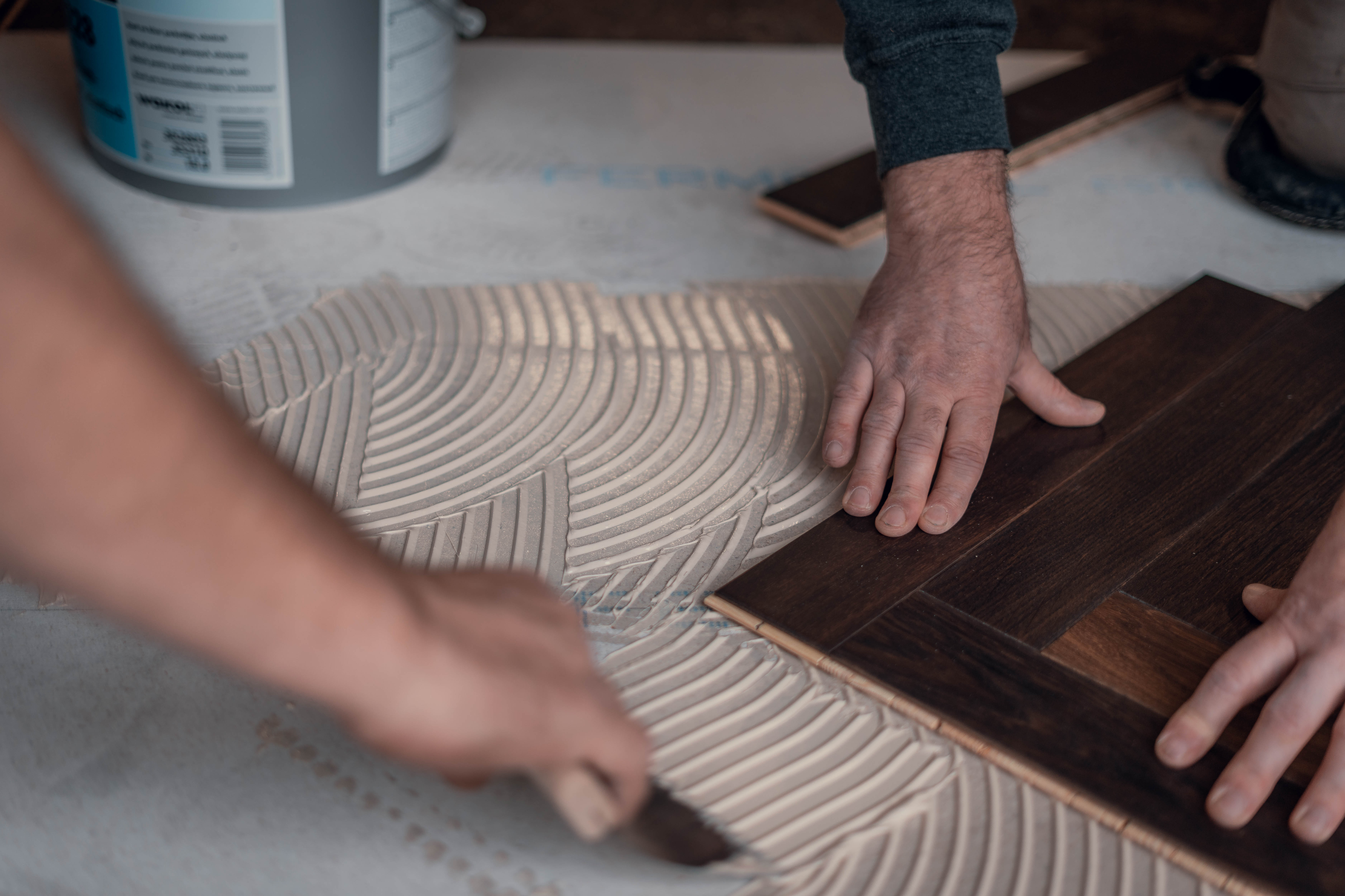 Team von Hauptstadt Parkettleger beim Auftragen von Kleber und Verlegen von Parkett