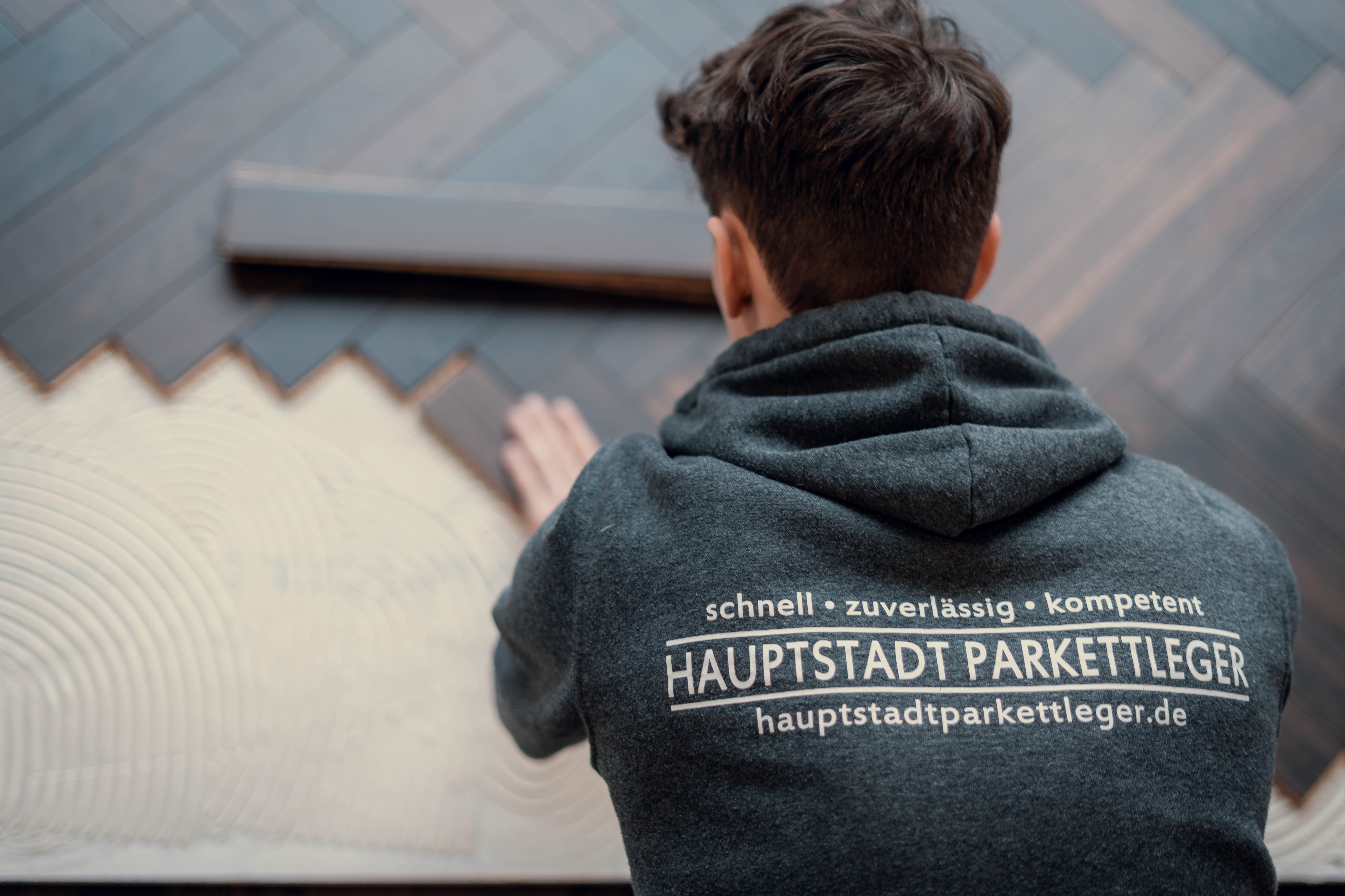 Handwerker von Hauptstadt Parkettleger verlegt neuen Parkettboden.