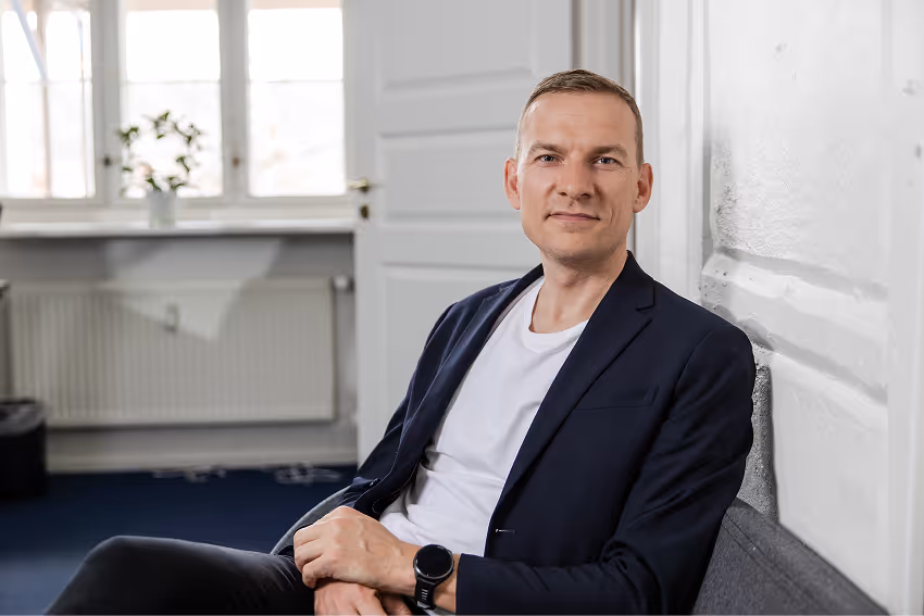 Portrætfoto af Tinsfeldt-partner i stol med neutral baggrund.