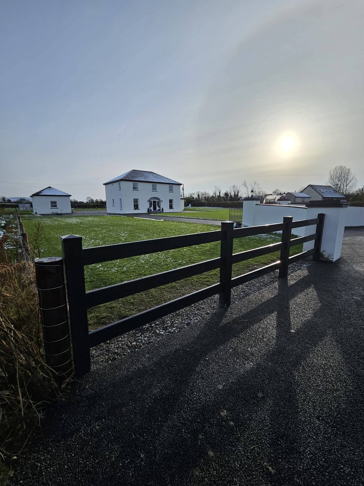 New wooden privacy fence with metal posts in a backyard under cloudy sky next to an old wooden fence and green trash bin.