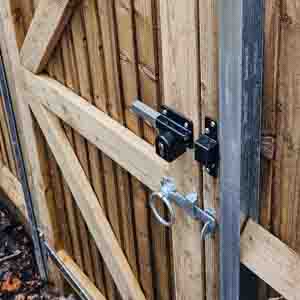 Framed wooden gate with black hinges and diagonal brace, installed on garden boundary.