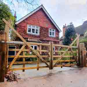 Double wooden driveway gates with decorative arched tops and galvanised hinges.