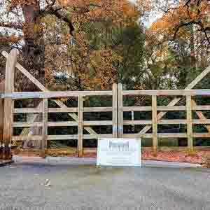 Five-bar timber field-style gates providing secure yet open access to a rural property.