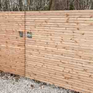 Smooth-rendered brick wall entrance with wooden gates providing driveway privacy.