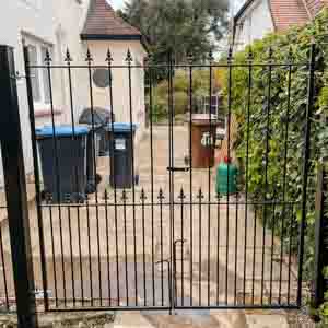 Modern metal-frame and timber-infill driveway gates beside residential fencing.