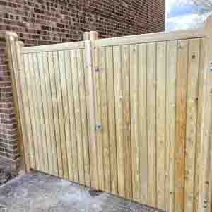 Closeboard wooden entrance gate with natural timber finish beside a garden fence.