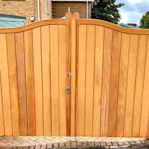Solid tongue-and-groove timber gates with curved tops and galvanised fittings.