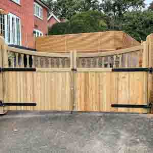 Wide double closeboard entrance gates providing driveway access in a rural setting.