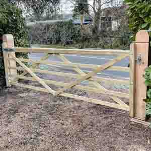 Framed ledged timber entrance gates installed on sturdy gateposts at a garden boundary.
