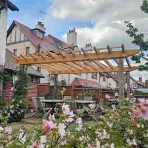 Bespoke pergola with climbing plants, enhancing a landscaped garden with fencing.