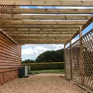 Timber-framed covered seating area with decorative lattice and open sides.