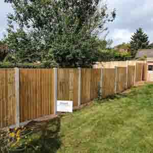 Timber panel fencing with concrete posts, installed along a landscaped lawn in East Grinstead.