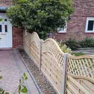 Timber panel fencing with curved lattice top, installed beside a brick wall for added height.