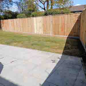 Panel fencing with concrete posts and smooth gravel board base beside a new patio area.