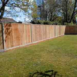 Closeboard fence with concrete posts and gravel boards installed on a sloped lawn.
