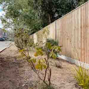 Closeboard fencing with concrete posts, gravel boards, and capping rail on a raised edge.