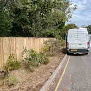 Closeboard timber fence with concrete posts and gravel boards beside a driveway entrance.