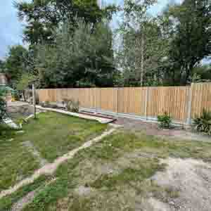 Closeboard fence with concrete posts and gravel boards along a landscaped lawn.