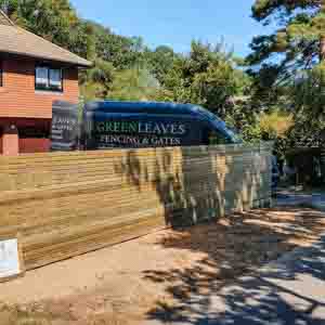 Contemporary slatted fence surrounding a raised patio with warm-toned paving.