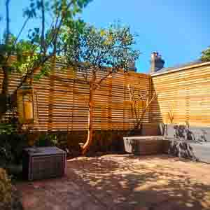 Golden-toned timber slatted fence surrounding a patio and seating area.
