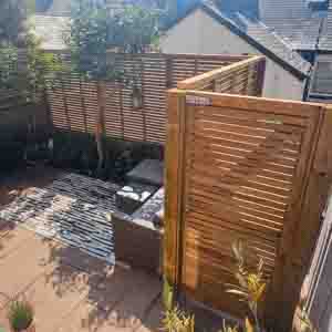 Contemporary slatted timber gate and screen forming a smart entrance to the garden.