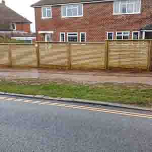 Modern slatted boundary fence following a roadside garden edge.