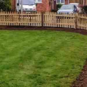 Curved timber picket fence enclosing a lawned garden with neat gravel edge.