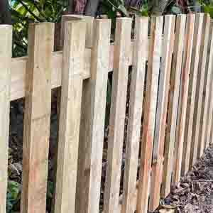 Close-up of weathered picket fence boards with even spacing and rounded tops.