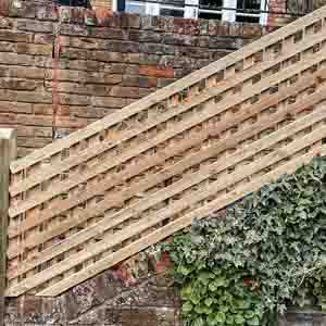 Closeboard fence with square-lattice trellis topper beside a brick retaining wall.