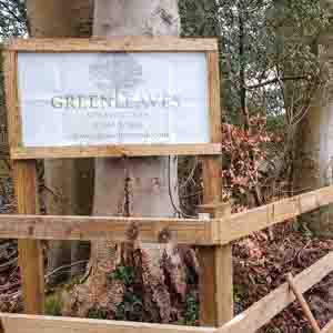 Wooden post and rail fencing with Green Leaves sign, installed along a rural garden boundary.