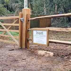 Timber post and rail fencing marking the entrance to a farm in rural West Sussex.