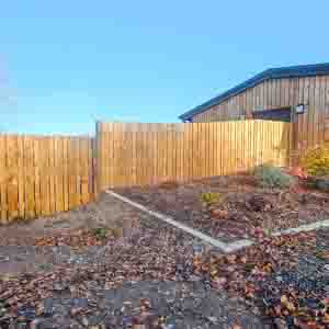 Timber fencing surrounding a farmyard with solid posts and gravel base.