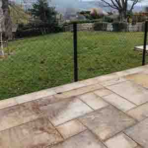 Modern metal post and mesh fence enclosing a garden patio area.