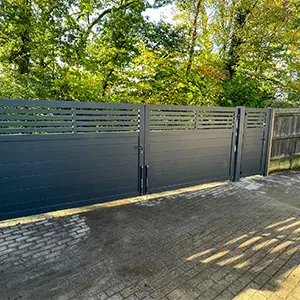 Metal driveway gates with slatted top section and matching side gate, installed by Green Leaves Fencing & Gates in East Grinstead.