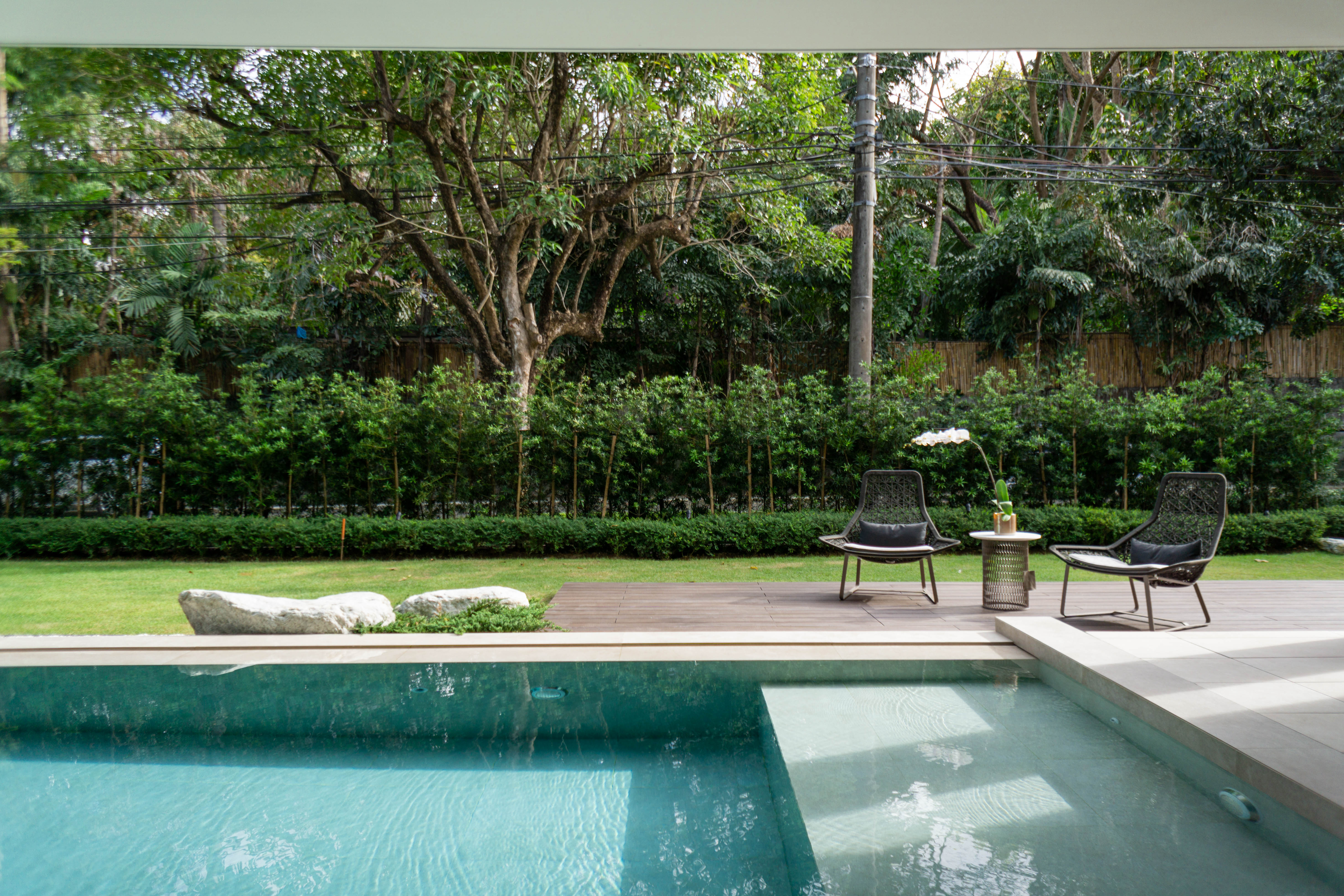 Bahay Huni — The poolside setting framed by backdrop of dense green hedges and natural elements creates an open and airy feel within the garden