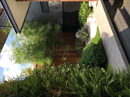 Walls of Green — The garden design maximizes the property's small spaces through the use of green walls, white gravel and boulder, and finely-textured shrubs.
