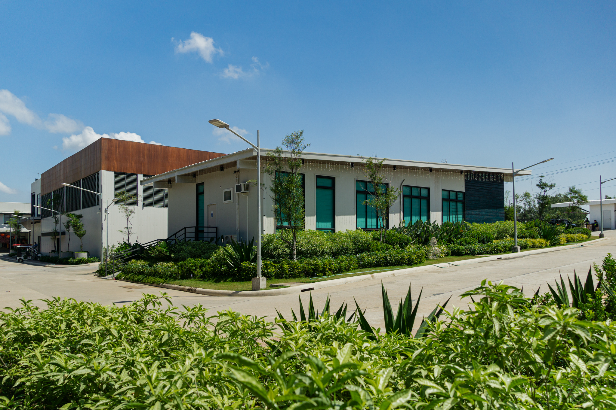 Amenities around the complex are framed with fine textured shrubs, lush planting, and small trees, creating a vibrant and inviting landscape.