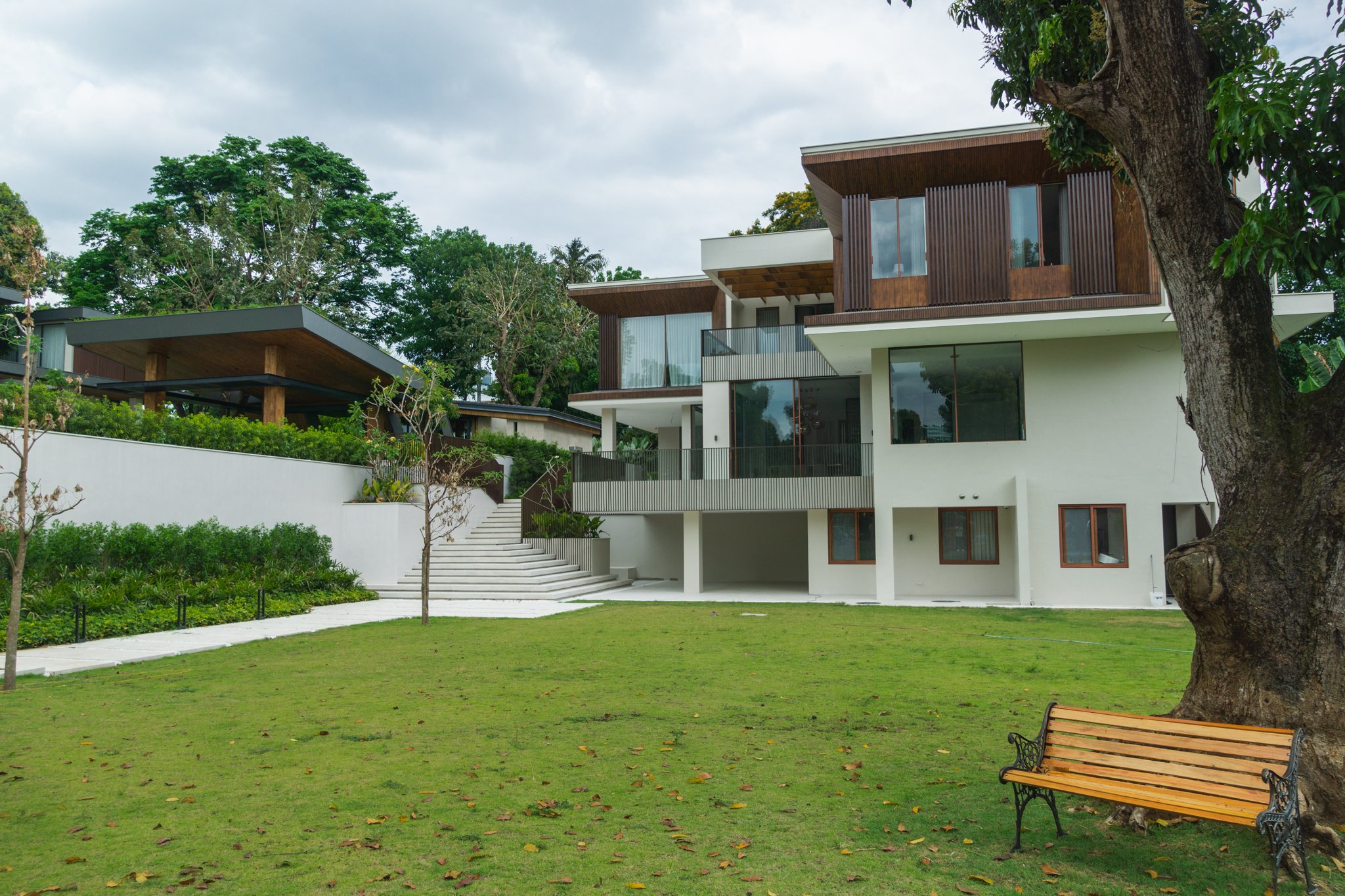 Casas La Vista — The terracced property also features an expansive lawn, with a wooden bench beside a tree, bordered with layered planting, providing the perfect space for thinking and relaxation