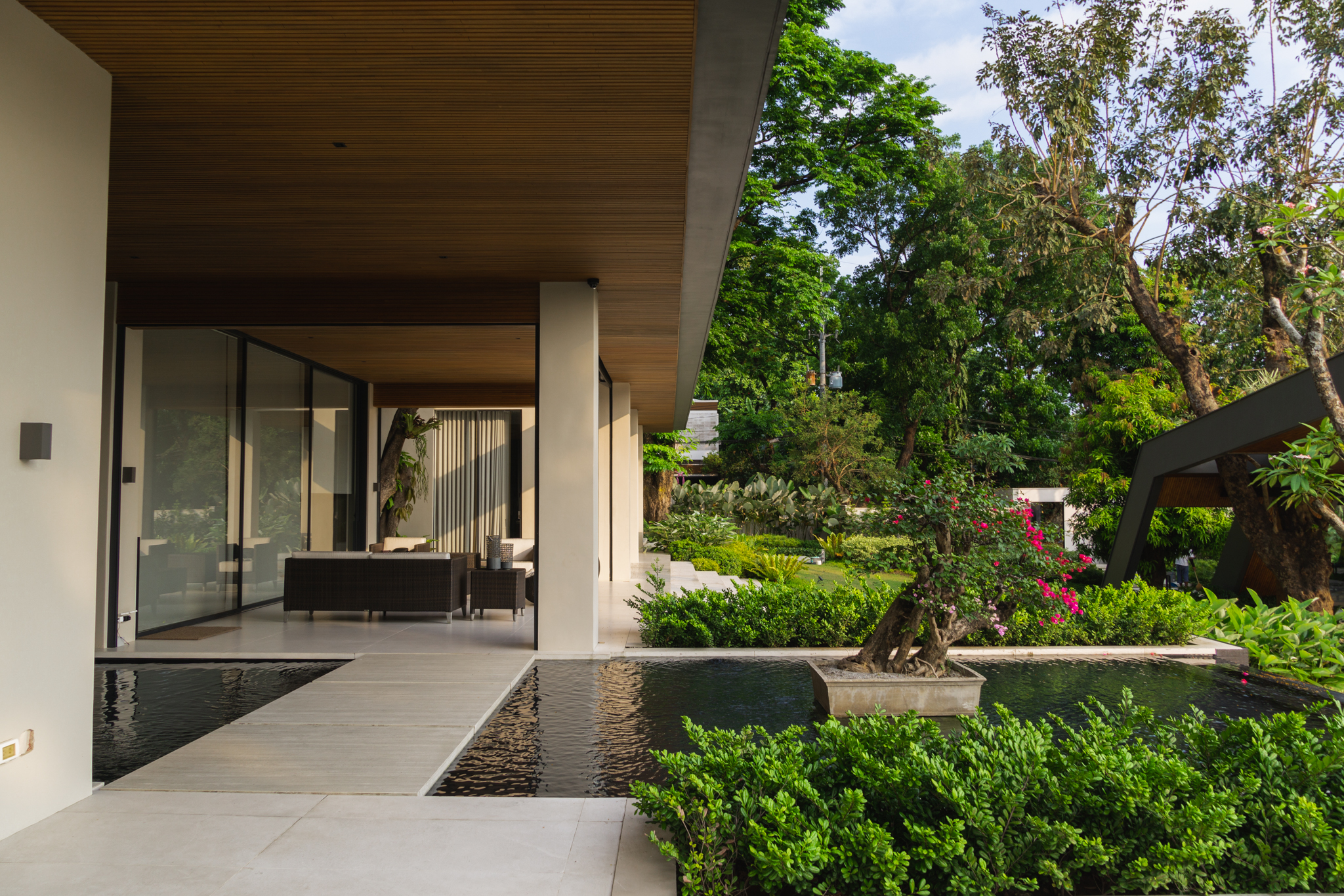 Casas La Vista — The outdoor living area features a Japanese-styled water feature that connects through the rest of the garden, all nestled within a lush tropical setting that creates a relaxing backdrop