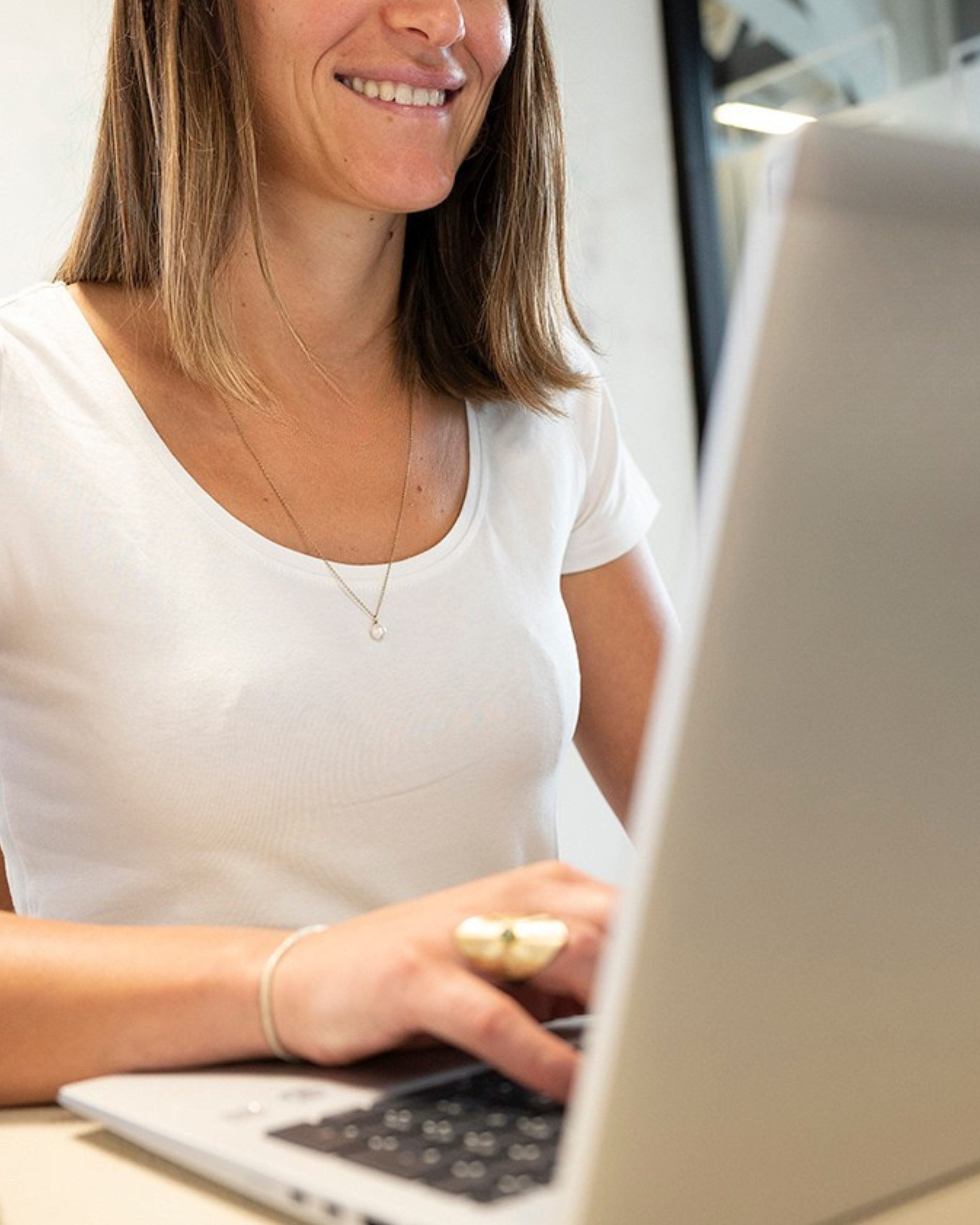 Femme rousse souriante debout près d'un tableau blanc avec des graphiques, tenant un marqueur.
