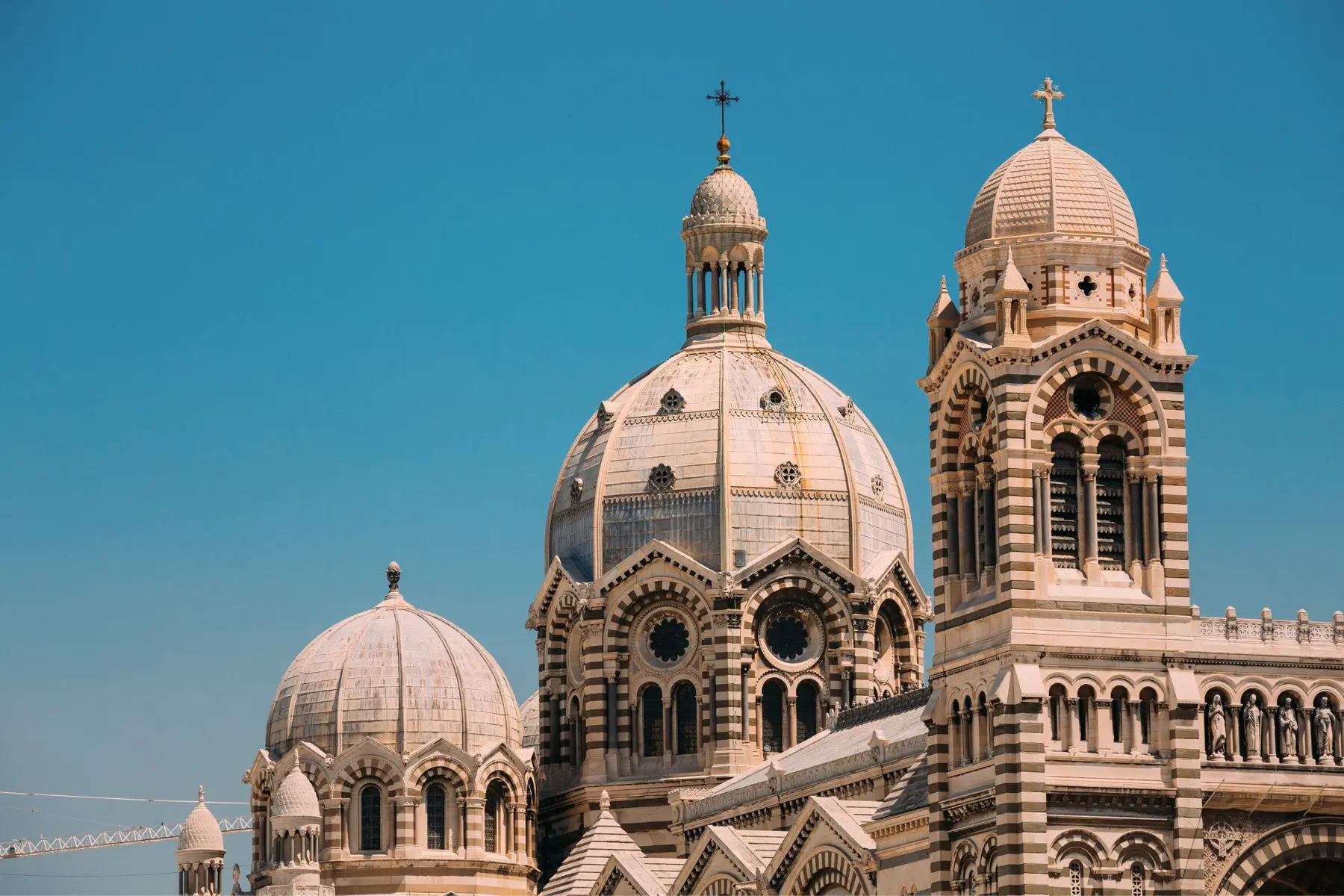 Close-up of the striped domes and towers of Marseille Cathedral against a clear blue sky