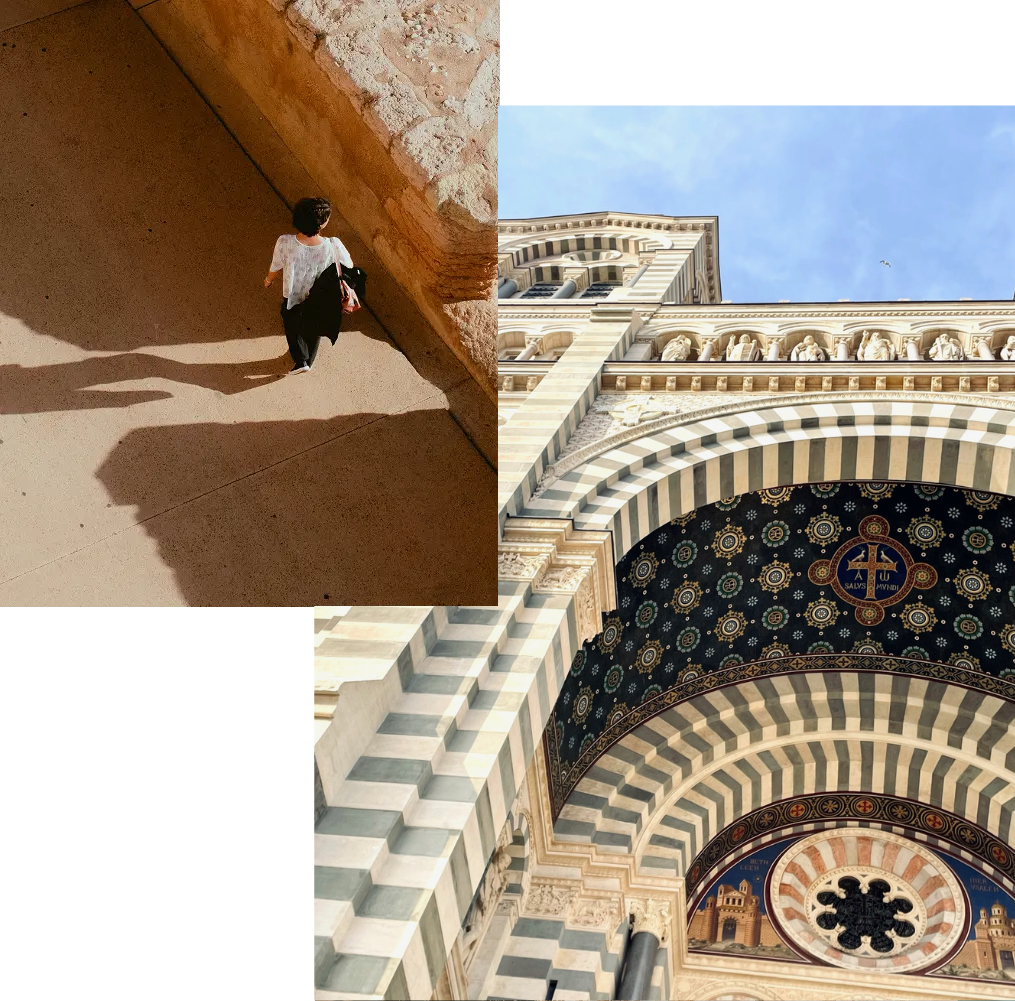 Person walking beside a sunlit stone wall near Notre-Dame de la Garde in Marseille; striped tower and ornate façade of the basilica against a clear sky.